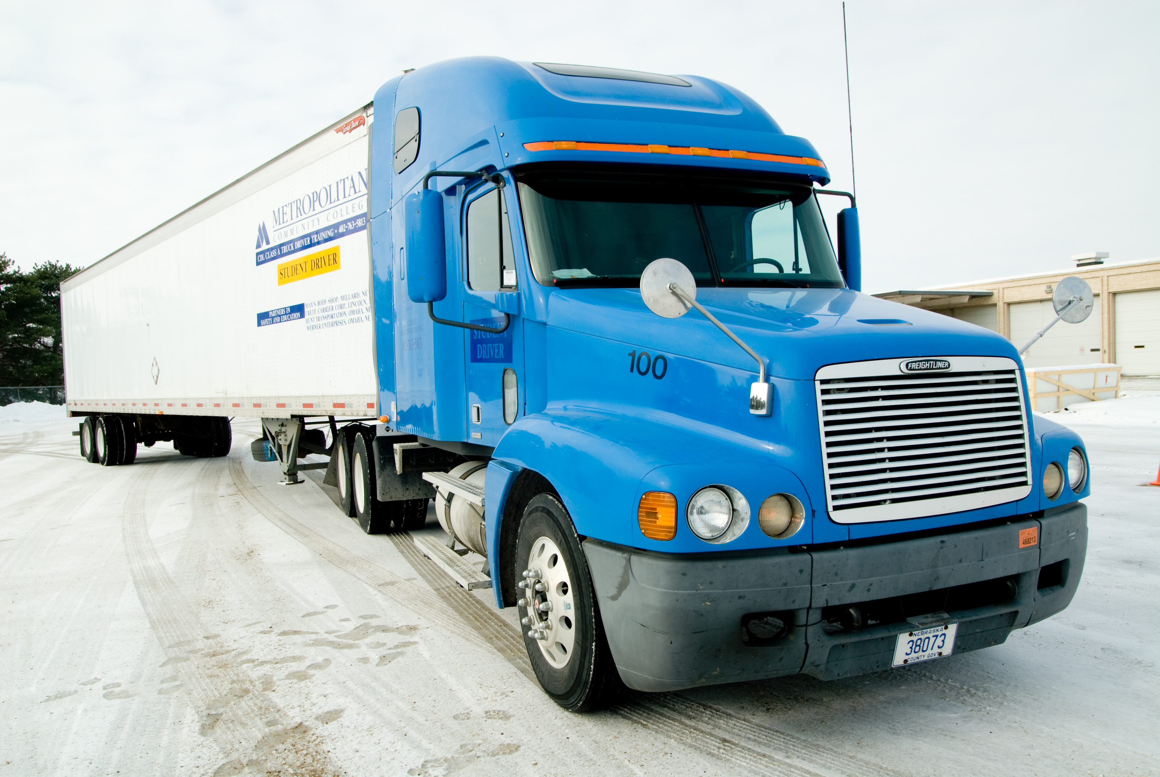 Blue semi truck with white trailer. 