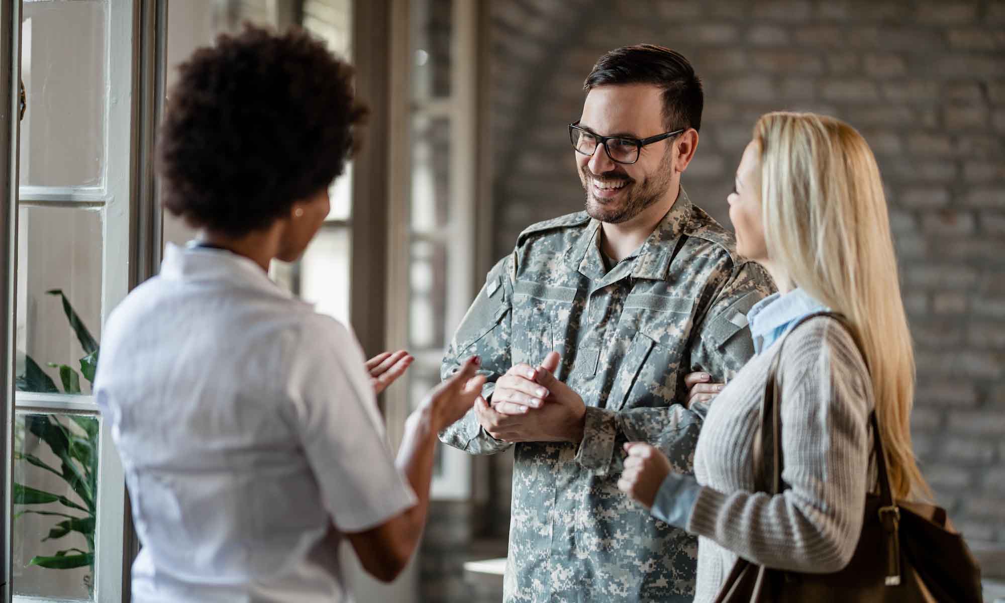 Military person conversing with two other people