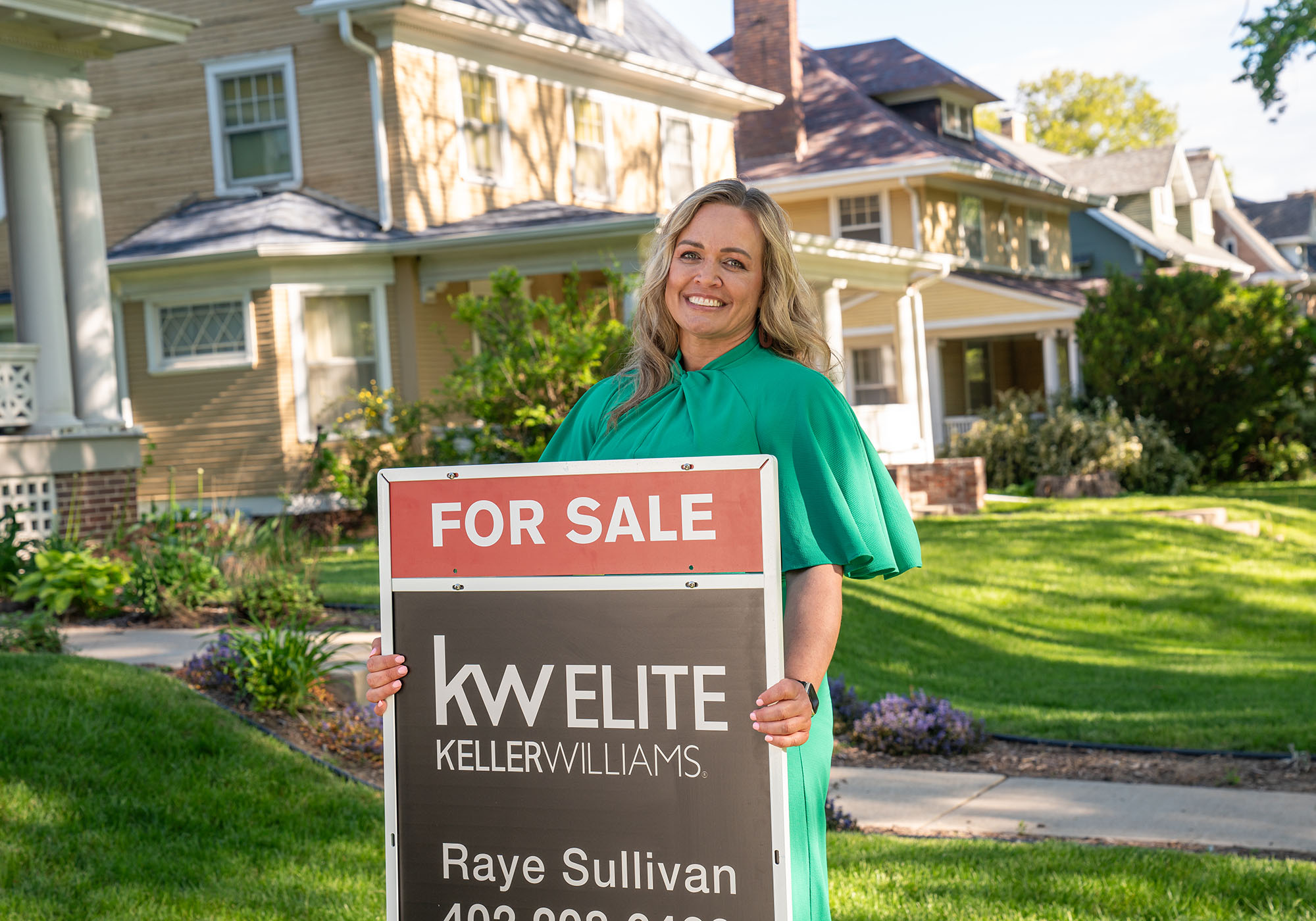 Female real-estate agent posing with for sale sign